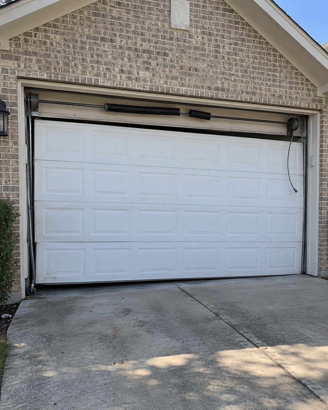 Crooked garage door with broken torsion spring before repair